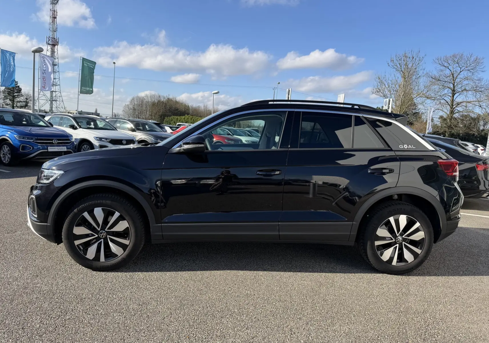 Profil côté gauche du Volkswagen T-Roc noir 2025 avec jantes alliage 17 pouces sur parking extérieur.