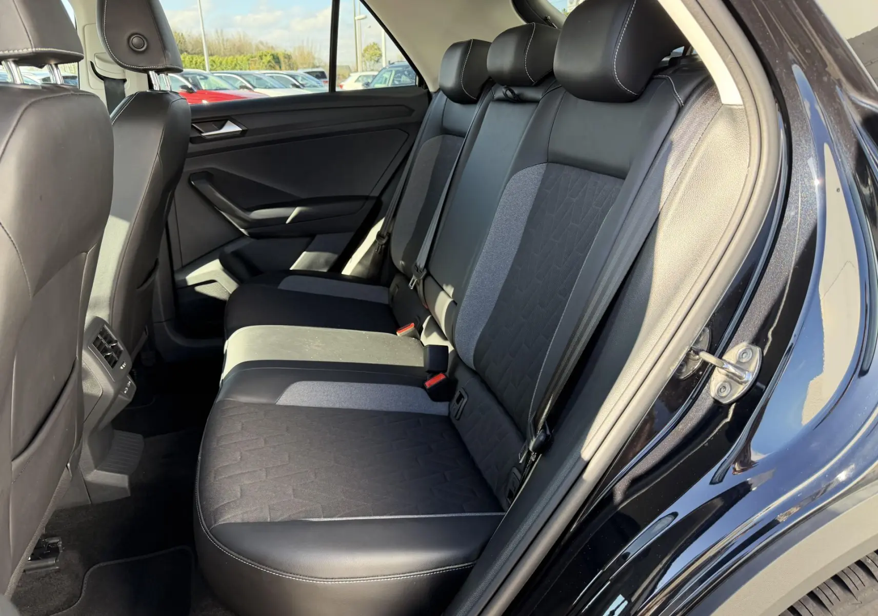 Vue intérieure côté droit des sièges arrière noirs en tissu et cuir du Volkswagen T-Roc 2025 avec portières ouvertes.