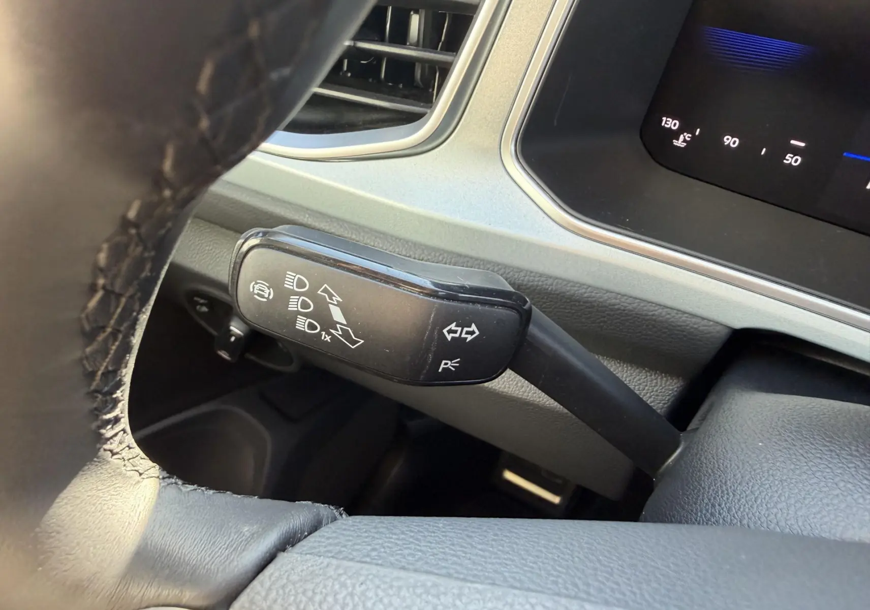 Gros plan sur la manette de clignotants noire à gauche du volant dans l’habitacle gris clair du Volkswagen T-Roc 2025.