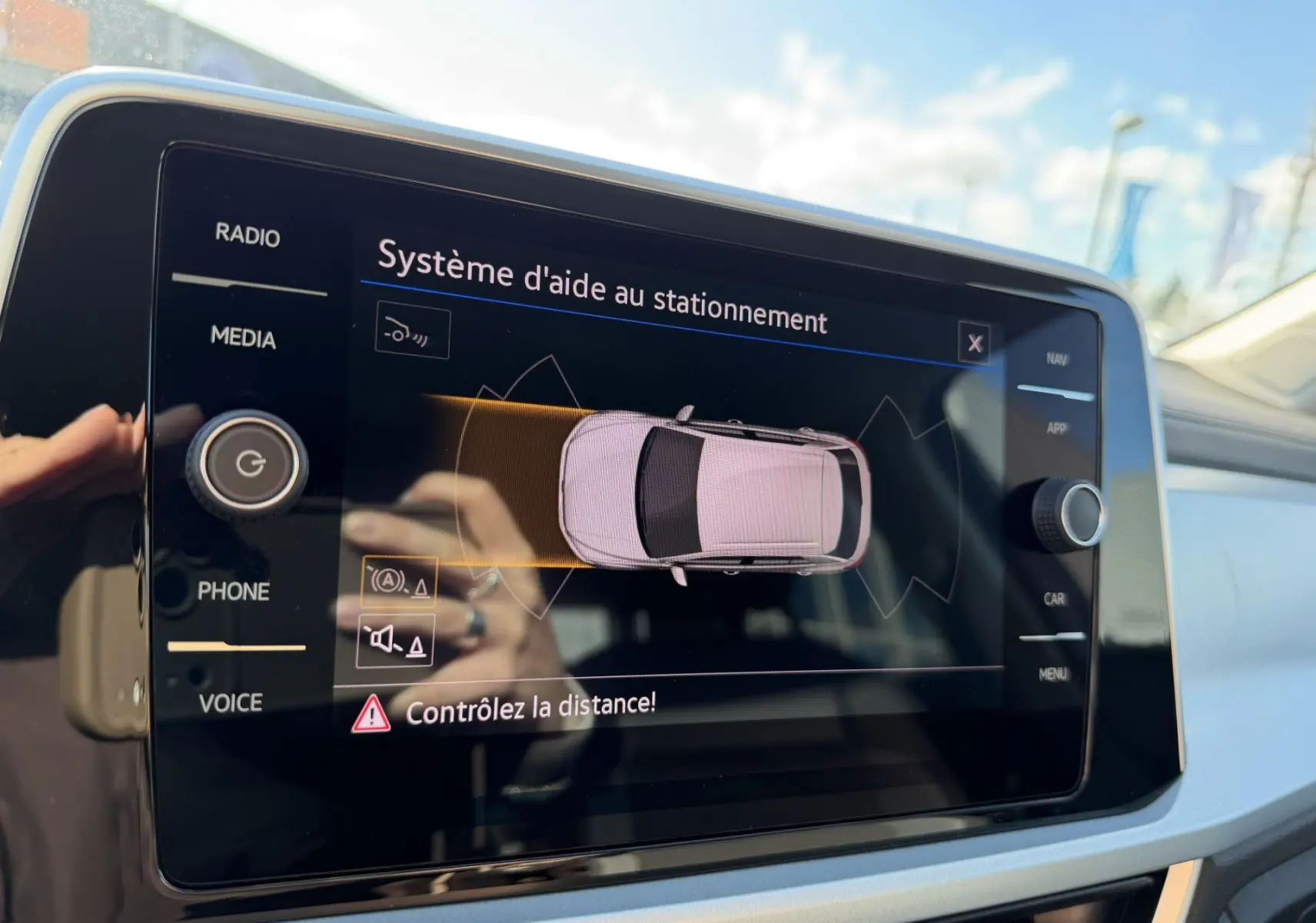 Écran tactile intérieur affichant le système d'aide au stationnement du Volkswagen T-Roc, vue rapprochée du tableau de bord.