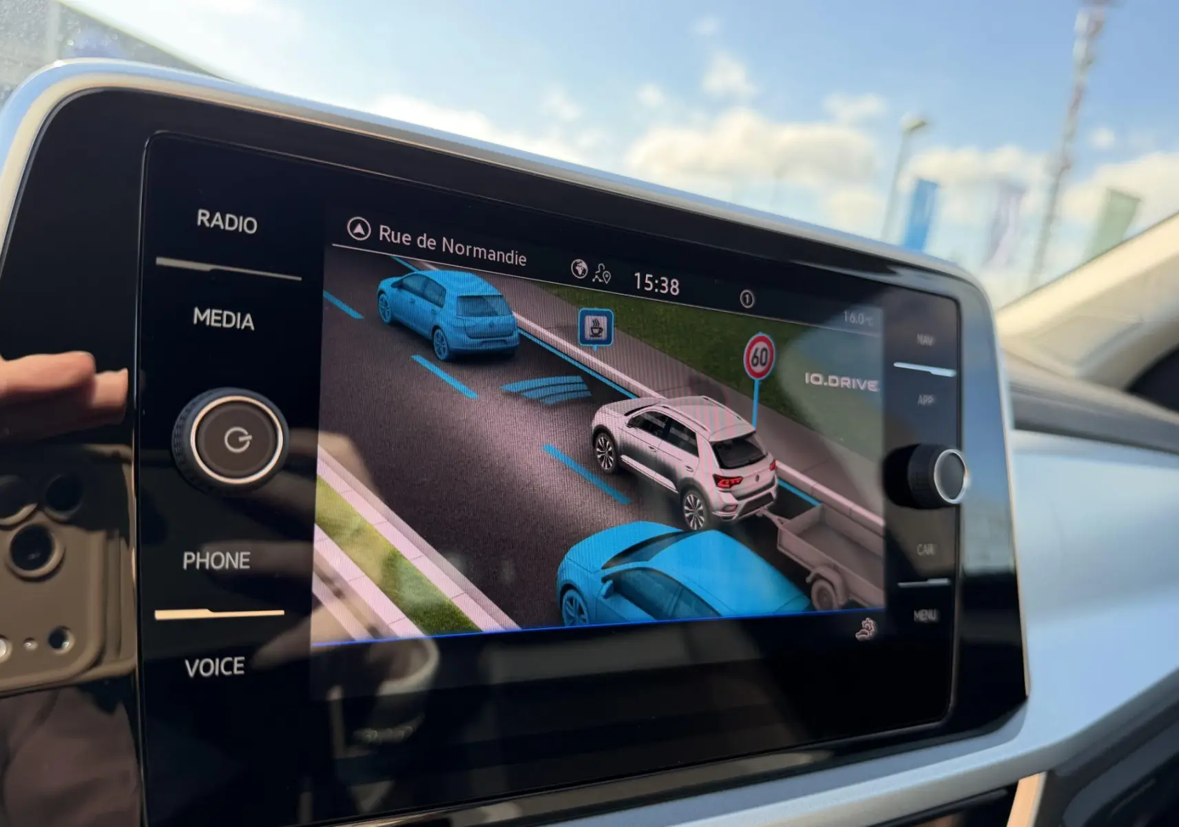 Écran tactile central montrant l’aide au stationnement avec vue 3D des véhicules et signalisation routière.