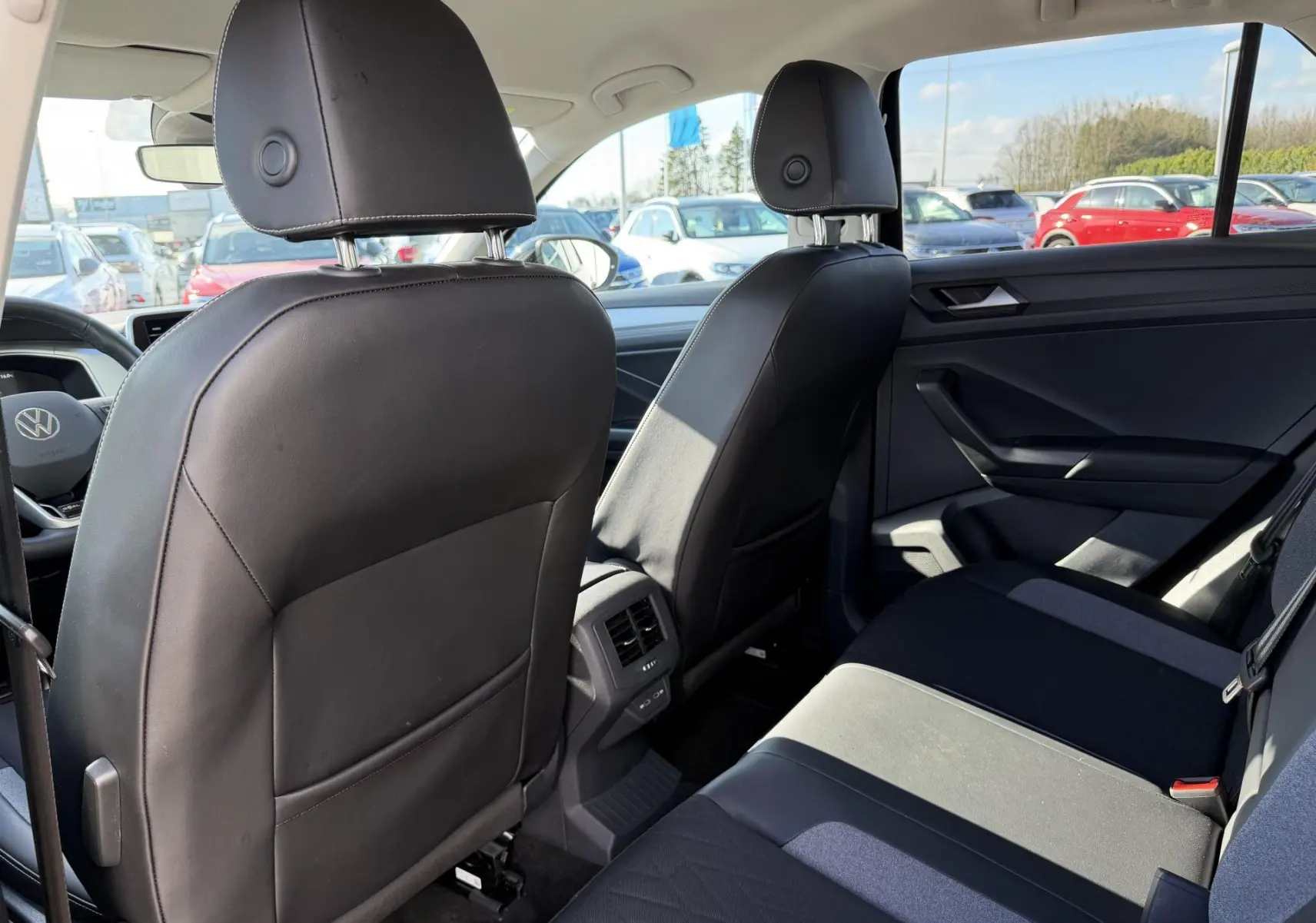 Vue intérieure arrière côté droit du Volkswagen T-Roc 2025 noir, montrant les sièges avant en cuir et la banquette arrière tissu.