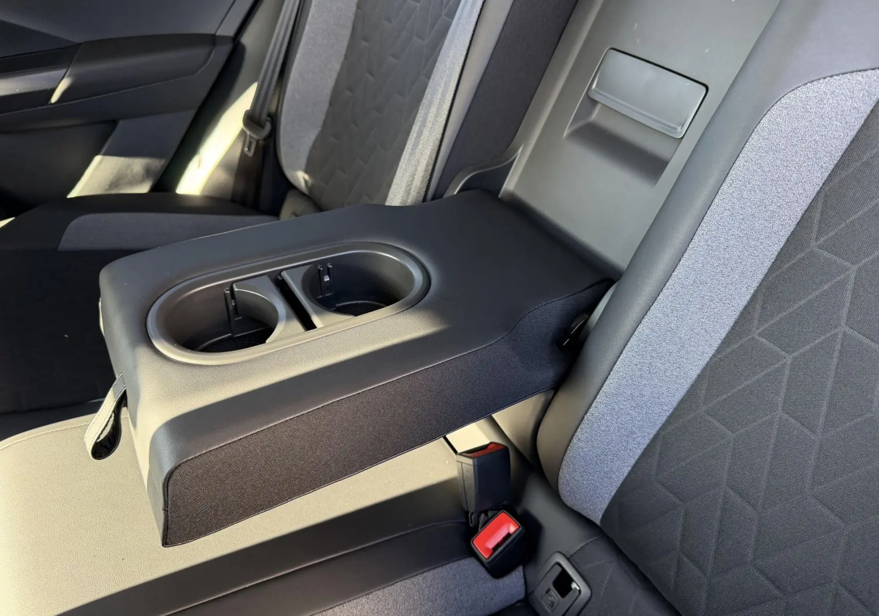 Vue rapprochée de l'accoudoir central arrière avec porte-gobelets sur la banquette tissu gris et noir du Volkswagen T-Roc 2025.