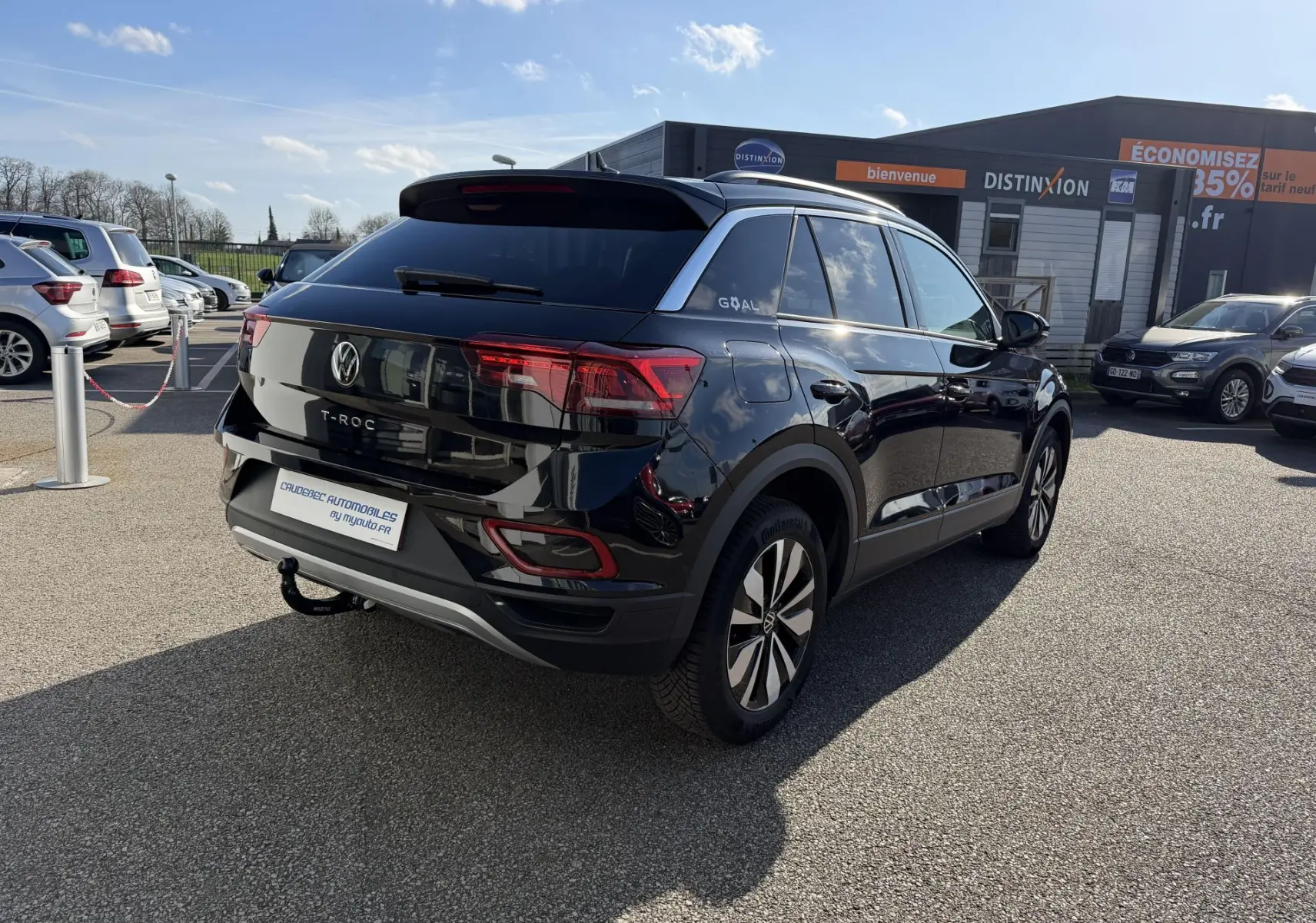 Volkswagen T-Roc noir vue 3/4 arrière droit avec attelage amovible sur parking extérieur.