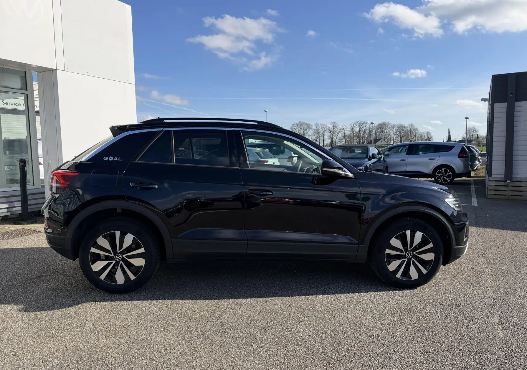 Vue de profil côté gauche d'un Volkswagen T-Roc noir 2025 avec jantes alliage 17 pouces et vitres surteintées.