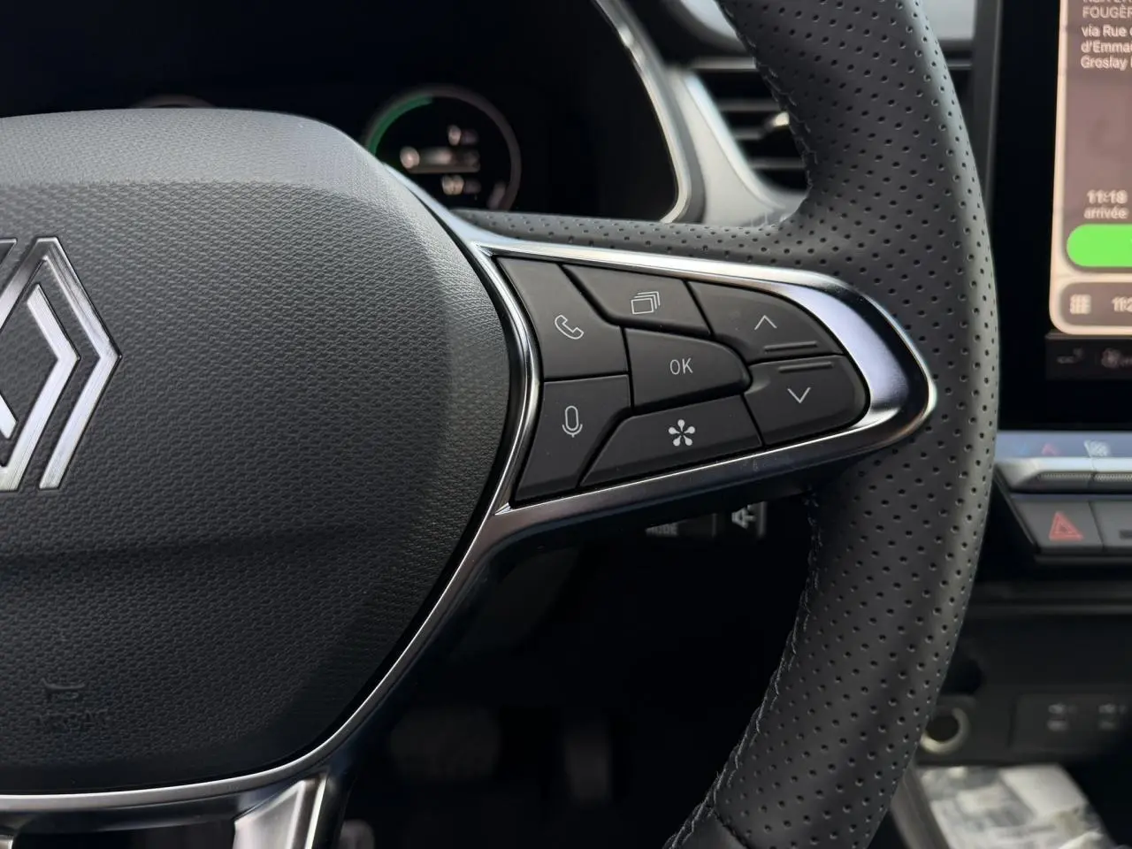 Gros plan sur le volant perforé noir du Renault Captur 2026 avec commandes multifonctions et logo central chromé.