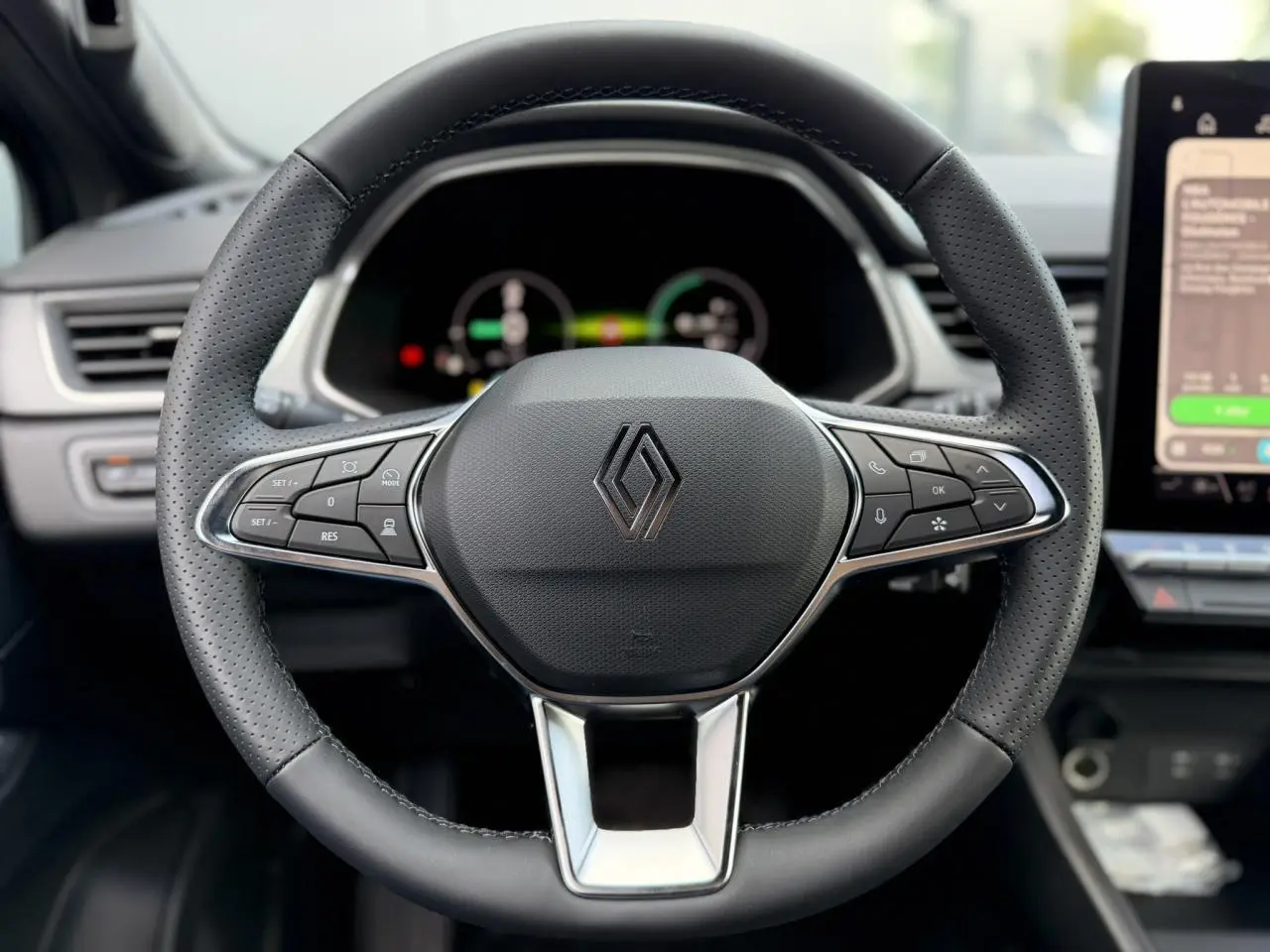 Vue rapprochée du volant noir perforé du Renault Captur 2026 avec commandes intégrées et logo central chromé.