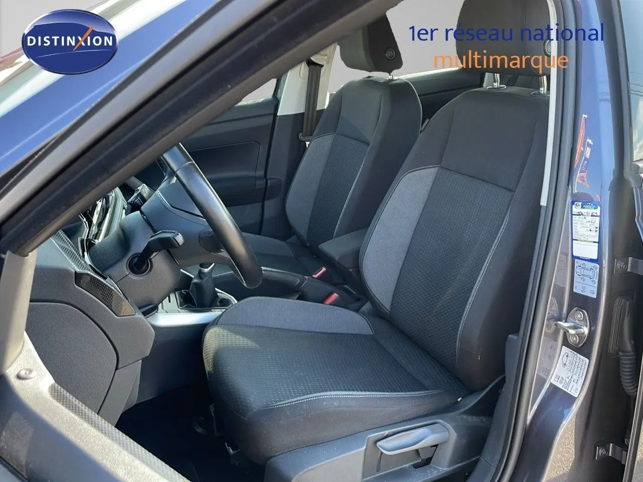 Vue intérieure côté conducteur du Volkswagen Taigo gris cendre 2022, sièges tissu gris et noir, boîte manuelle visible.