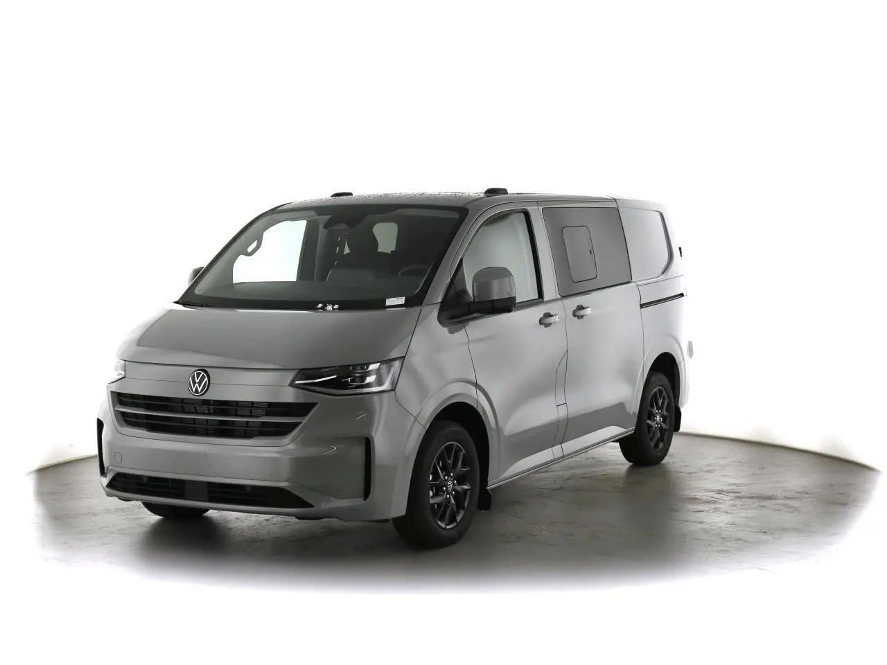 Volkswagen Transporter T7 gris Stone vu en 3/4 avant droit avec jantes alliage noir brillant et vitres latérales surteintées.