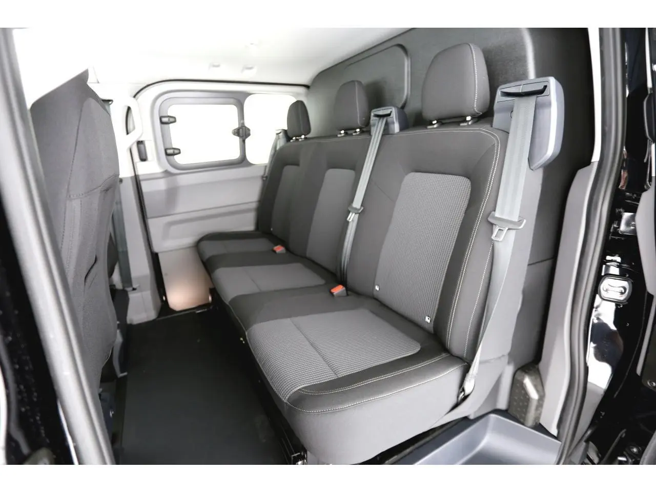 Vue intérieure côté droit montrant la banquette arrière grise du Volkswagen Transporter T7 ProCab 2025 avec ceintures de sécurité.