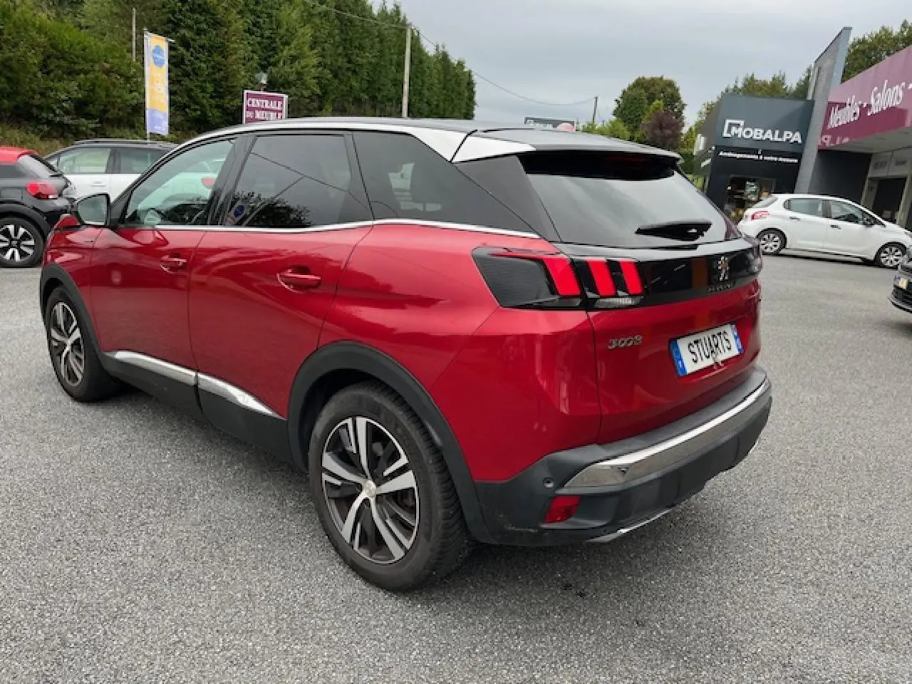 Vue 3/4 arrière droite d'un Peugeot 3008 rouge Ultimate avec toit noir et jantes alliage bi-ton.