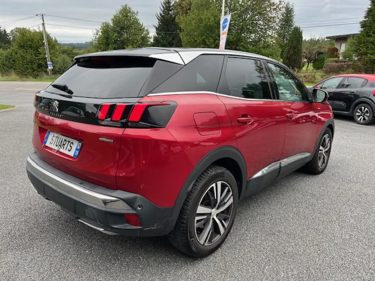 Vue 3/4 arrière droite d'un Peugeot 3008 rouge Ultimate avec toit noir et jantes alliage bi-ton diamantées.