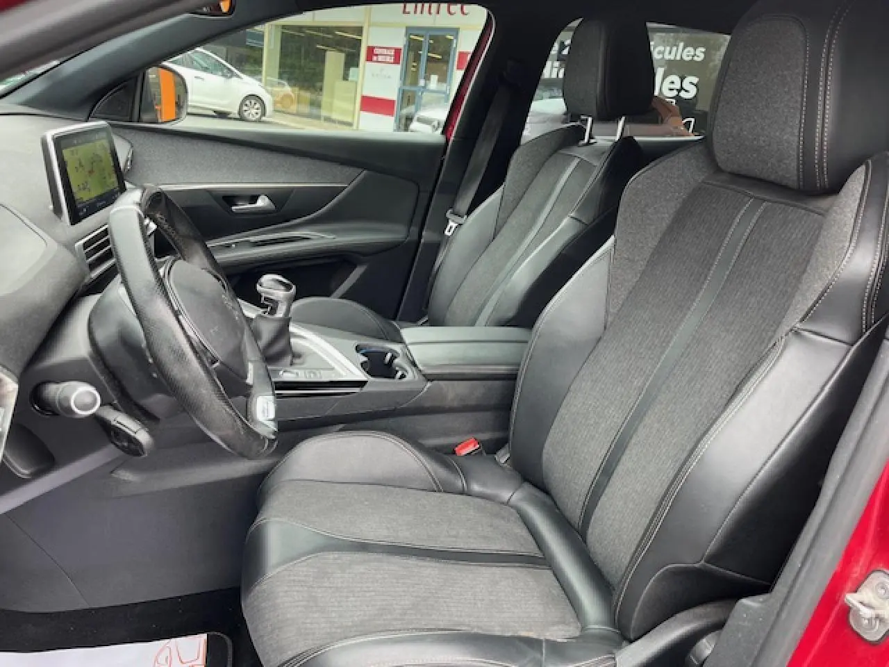 Intérieur avant du Peugeot 3008 GT Line 2019 rouge, sièges TEP et tissu noirs avec volant cuir perforé.