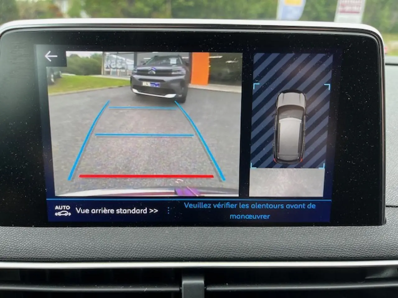 Écran de caméra de recul montrant l'arrière d'un Peugeot 3008 rouge Ultimate avec lignes de guidage bleues et rouges.