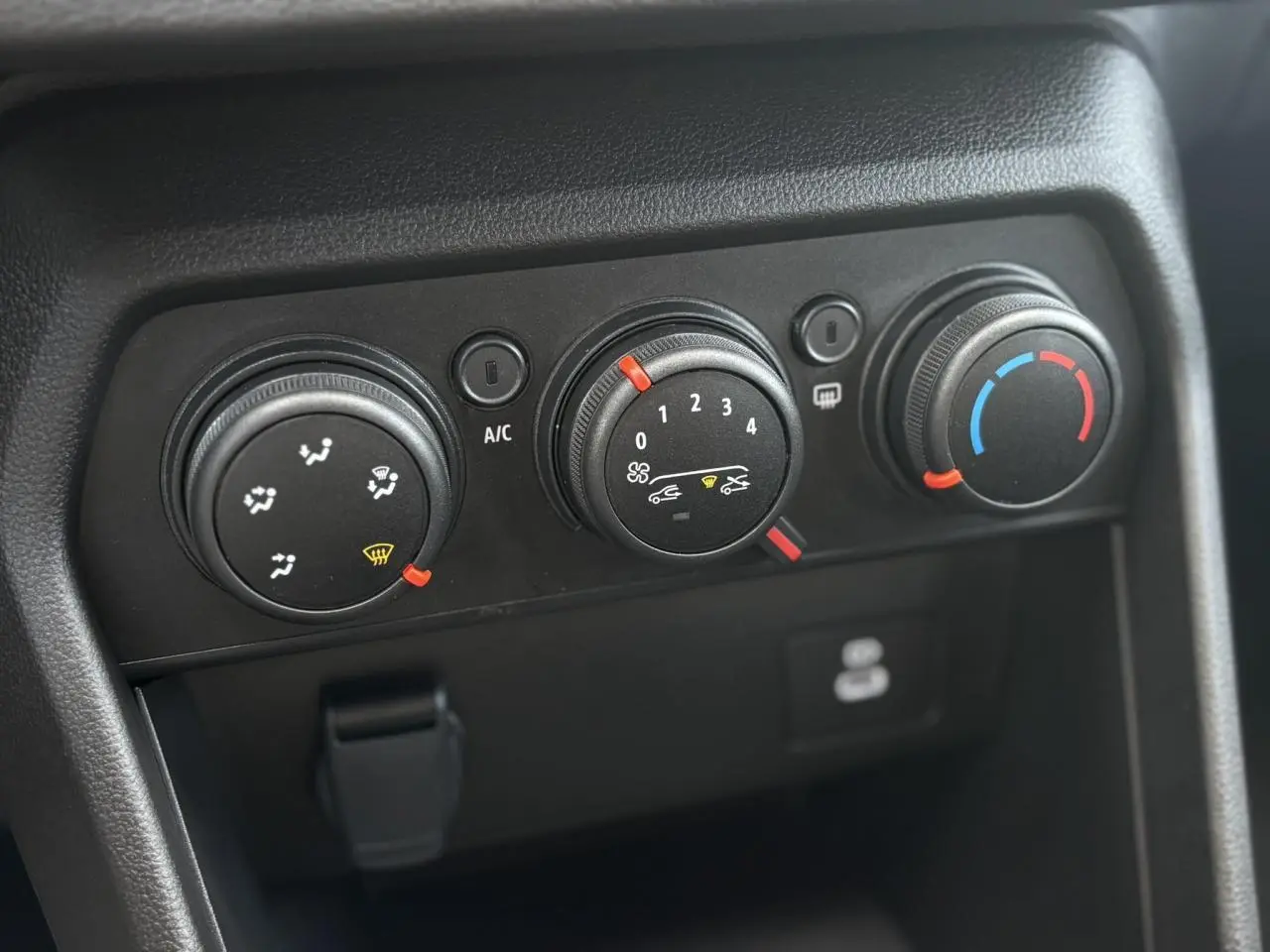 Gros plan sur les commandes de climatisation manuelle noires du tableau de bord de la Dacia Sandero Stepway 2025.