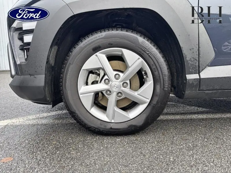 Gros plan sur la roue avant gauche d'un Hyundai Kona 2023 Denim Blue perlé métallisé avec jante alu cinq branches.