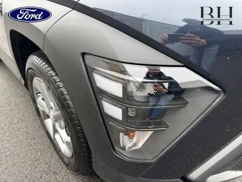 Gros plan sur le phare avant droit d'un Hyundai Kona 2023 Denim Blue perlé métallisé, soulignant ses lignes modernes et jante alu.