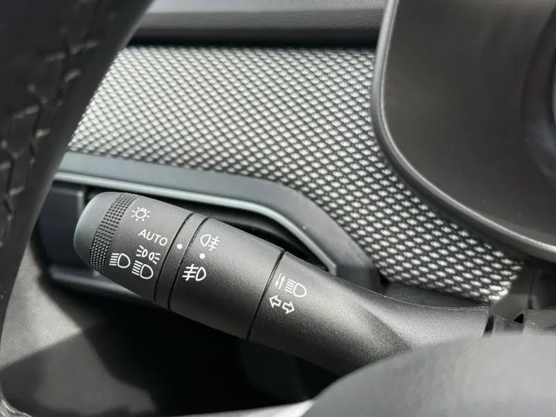 Gros plan sur la commande des feux du tableau de bord du Dacia Jogger 2025, intérieur noir texturé.