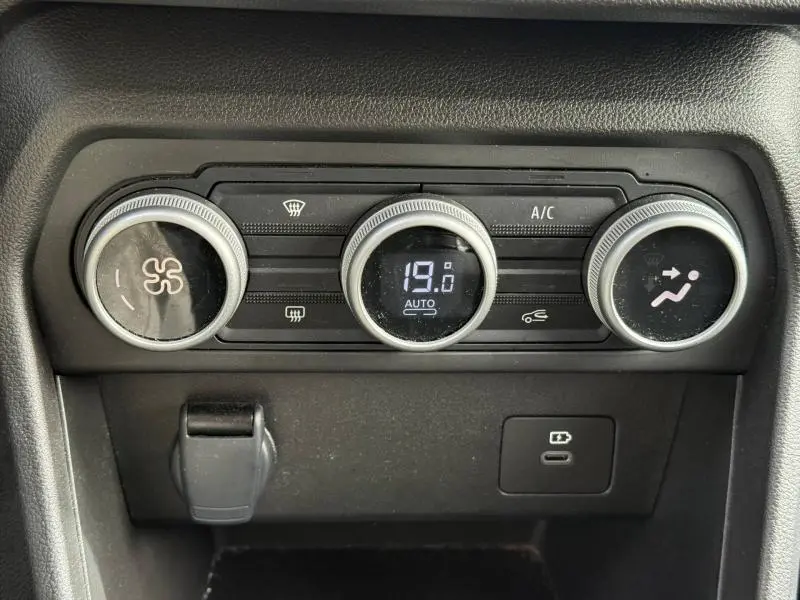 Gros plan sur les commandes de climatisation du Dacia Jogger 2025, avec affichage digital et boutons rotatifs noirs.
