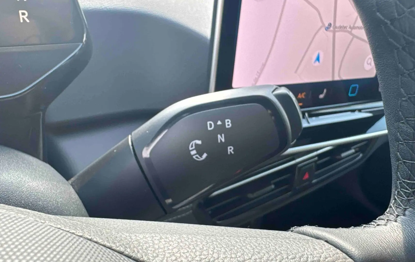 Gros plan sur le levier de vitesses manuel noir du Volkswagen ID.3 2025, avec écran tactile et tableau de bord partiellement visibles.
