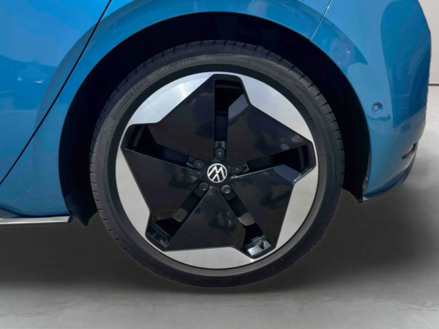 Gros plan sur la roue avant droite bleu métallisé d'une Volkswagen ID.3 avec jante alliage bicolore noire et argent.