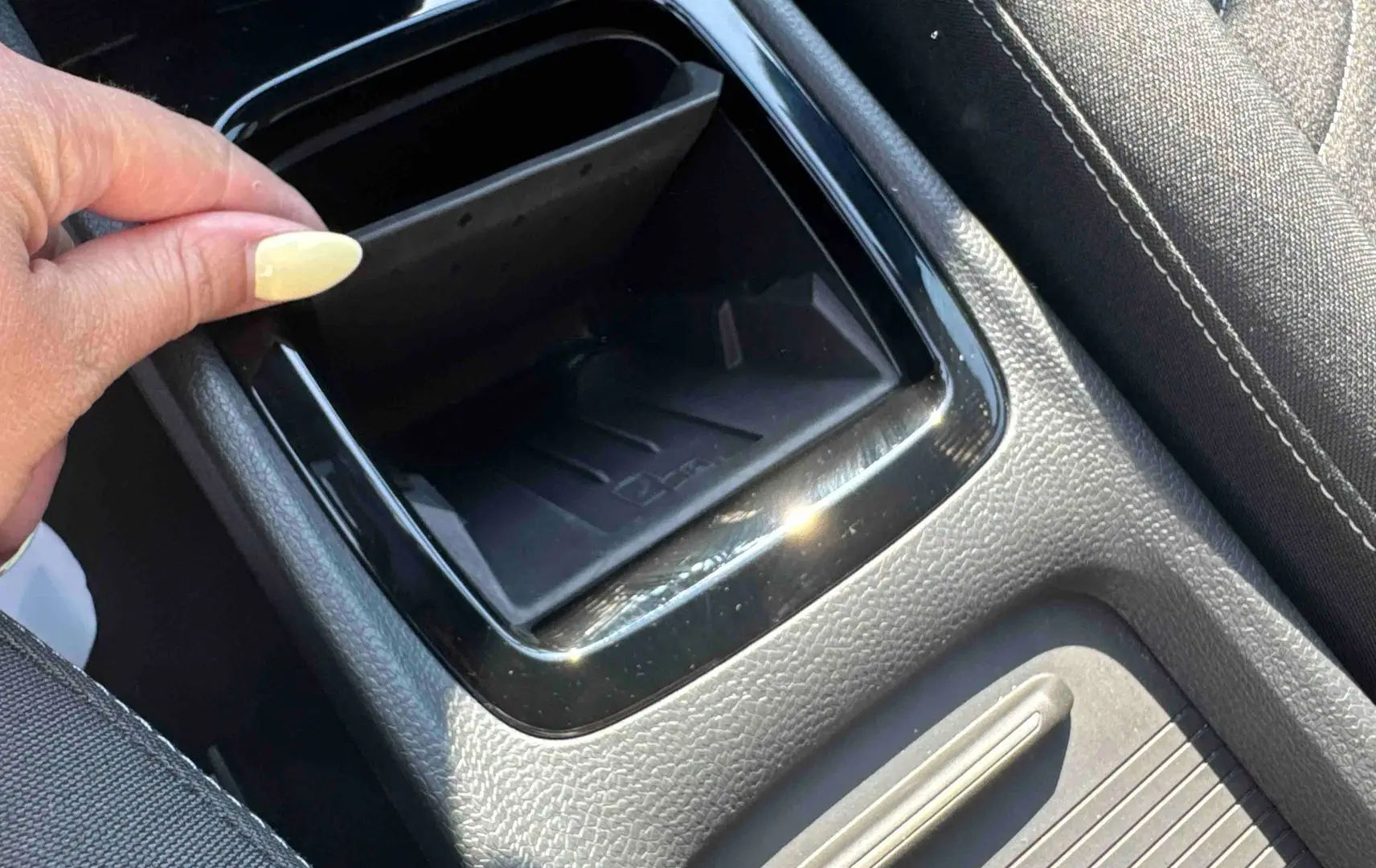 Détail de la console centrale noire avec rangement ouvert et siège tissu gris dans une Volkswagen ID.3 2025.