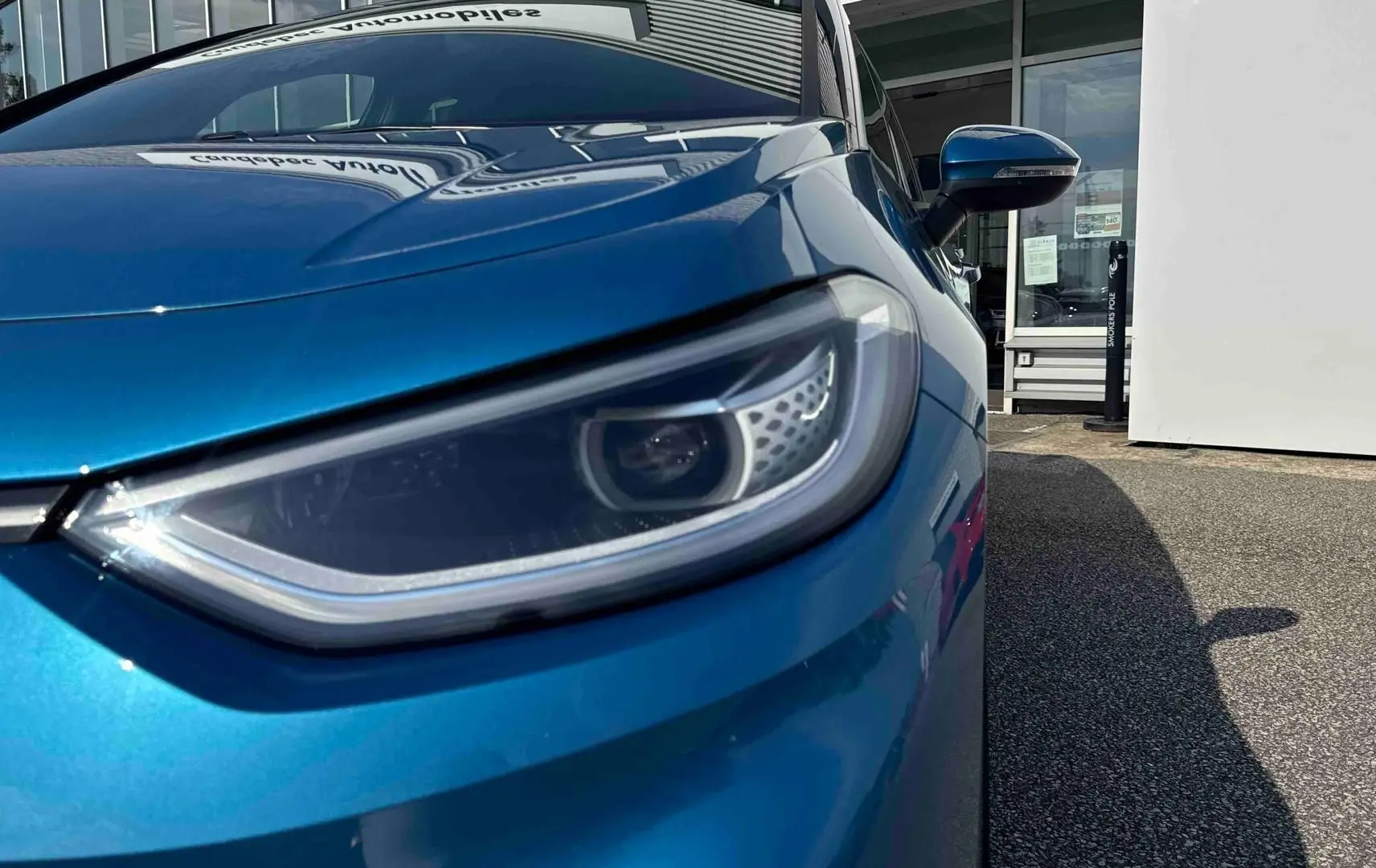 Gros plan sur le phare avant droit d’une Volkswagen ID.3 2025 bleu métallisé avec rétroviseur assorti.
