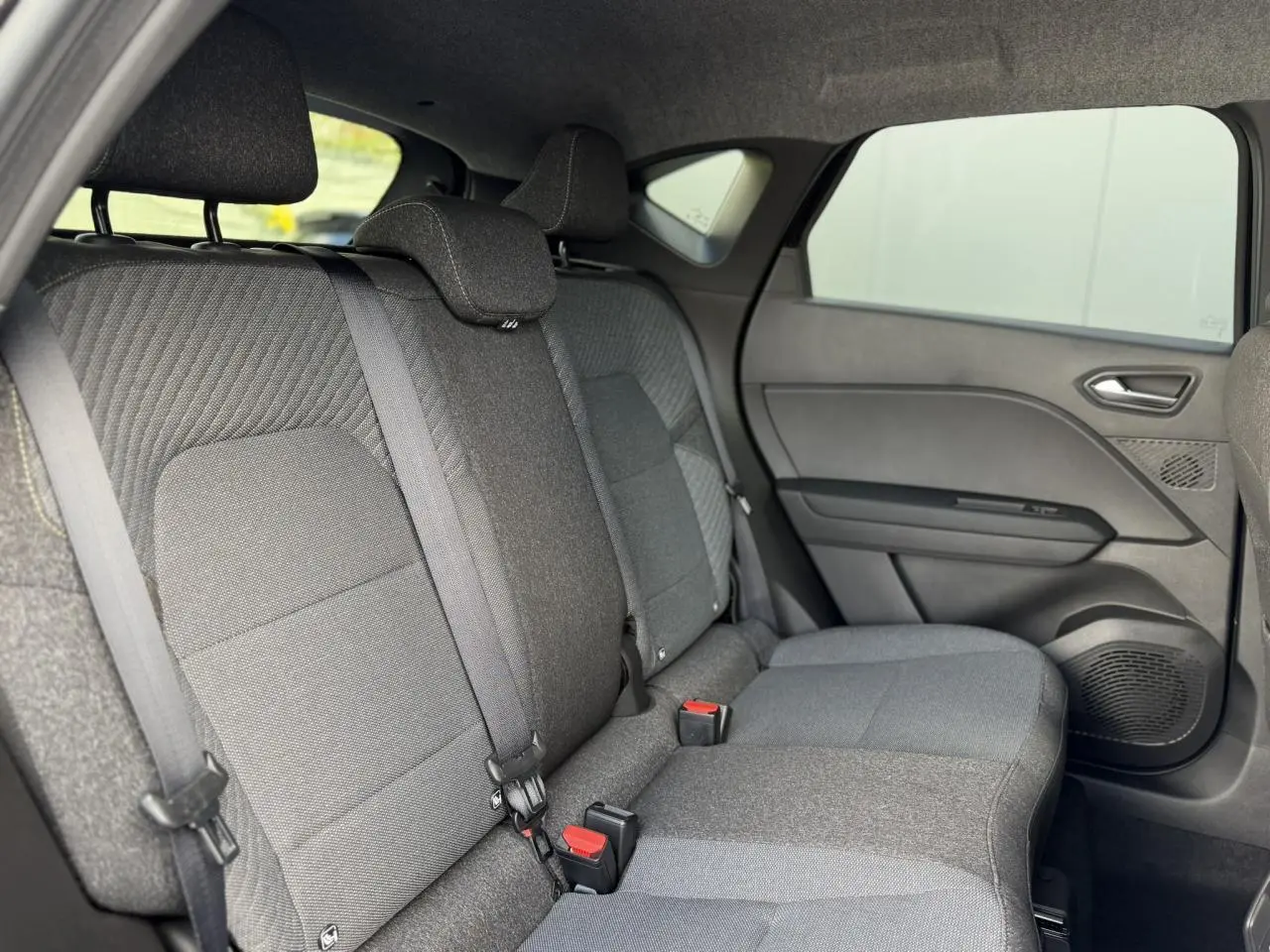 Vue intérieure côté droit des sièges arrière gris foncé du Renault Captur 2026 avec ceintures de sécurité et garnitures tissu.