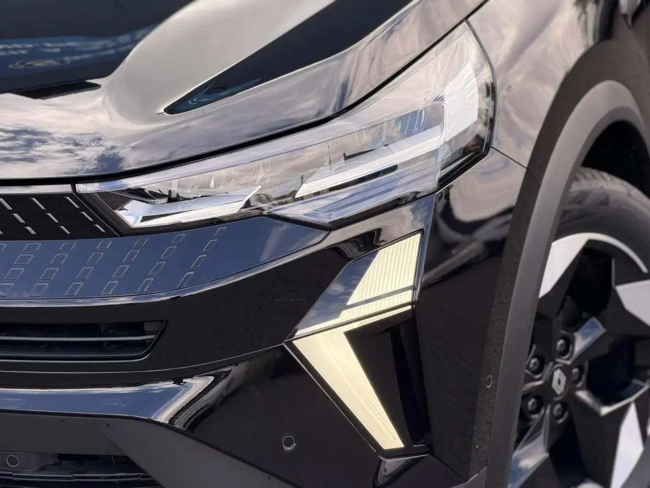 Gros plan sur l’avant droit noir étoilé du Renault Captur 2026, mettant en valeur les phares LED et la jante aluminium 18 pouces.