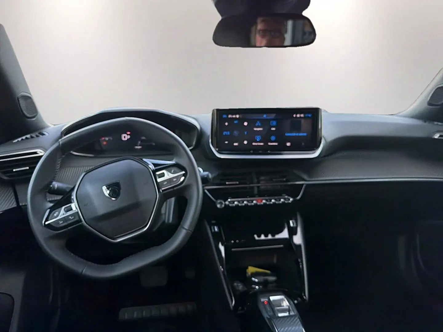 Vue intérieure avant du Peugeot 2008 1.2 hybrid 145 allure e-dcs6, tableau de bord et volant multifonction noirs.