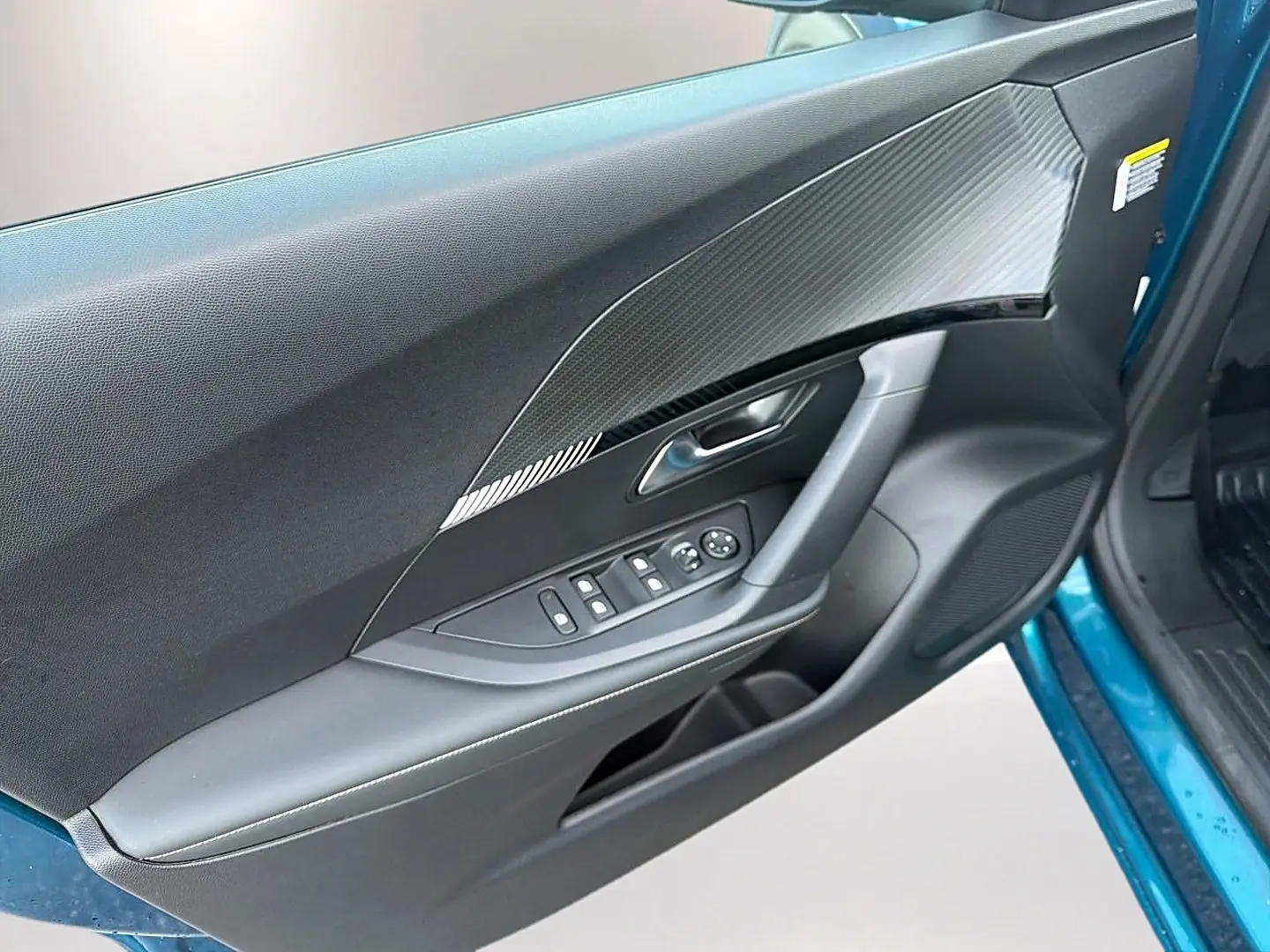 Vue intérieure côté gauche de la porte avant bleu obsession d’un Peugeot 2008 avec commandes de vitres et habillage noir texturé.