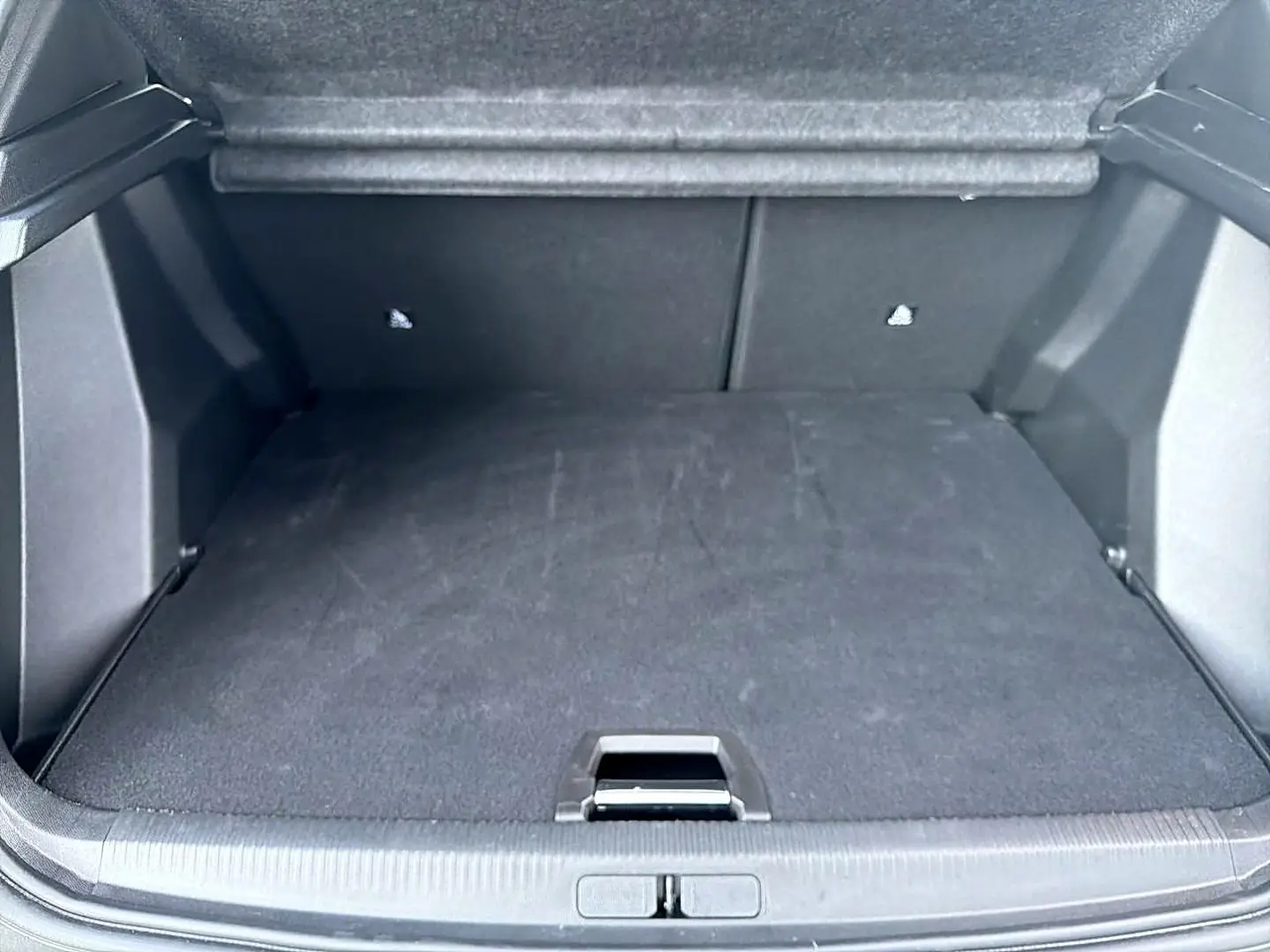 Coffre ouvert du Peugeot 2008 bleu obsession, vue arrière montrant l'espace de chargement vide et tapis noir.