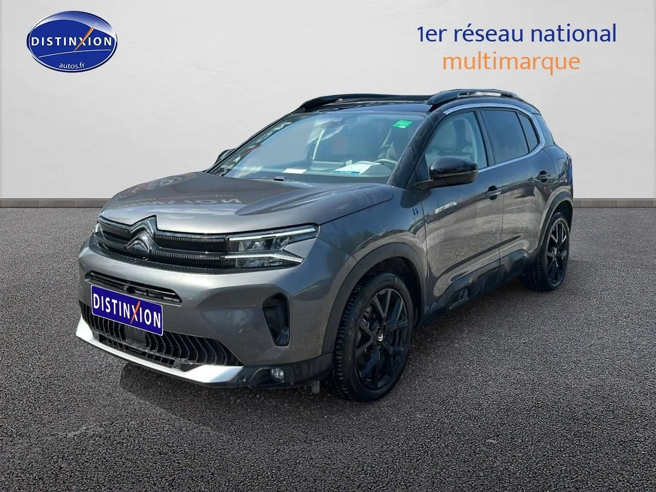 Citroën C5 Aircross gris platinium en 3/4 avant droit, avec jantes noires et barres de toit visibles.