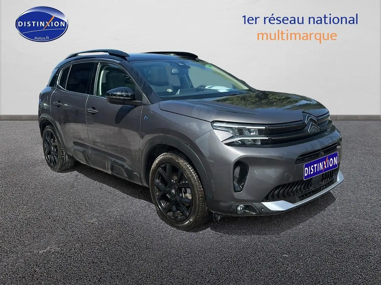 Vue 3/4 avant gauche du Citroën C5 Aircross gris platinium avec jantes noires et barres de toit visibles.