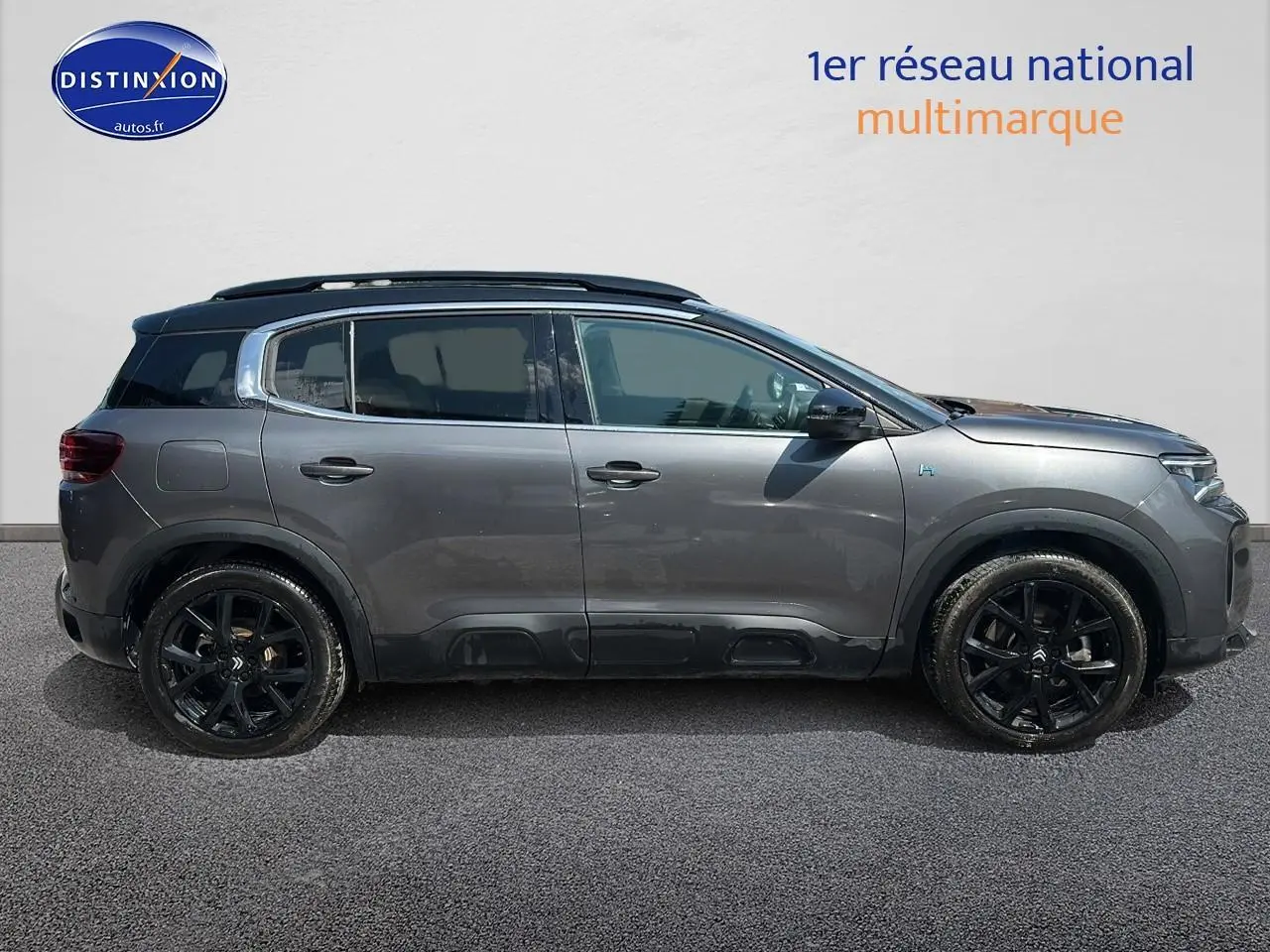 Profil côté gauche du Citroën C5 Aircross gris platinium avec jantes noires et barres de toit visibles.