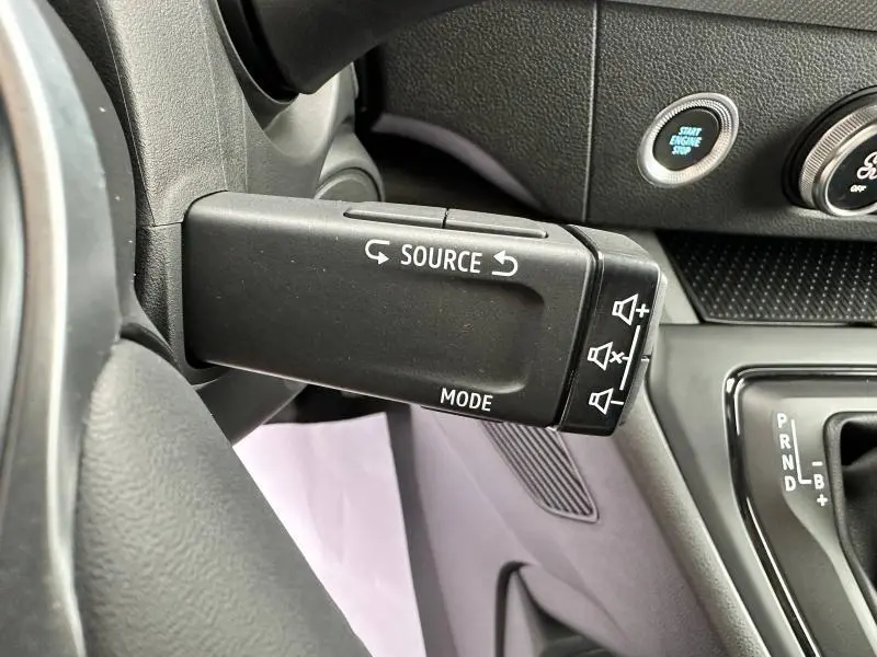 Gros plan sur la commande de mode audio à gauche du volant dans l'habitacle du Nissan Townstar blanc 2024.