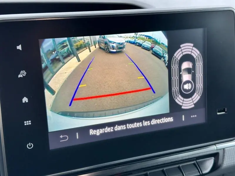 Écran tactile du Nissan Townstar blanc montrant la caméra de recul avec lignes de guidage et radar de stationnement actif.