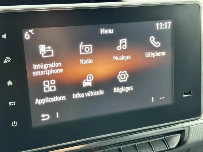 Écran tactile central du Nissan Townstar blanc minéral 2024 affichant le menu multimédia avec radio et téléphone.