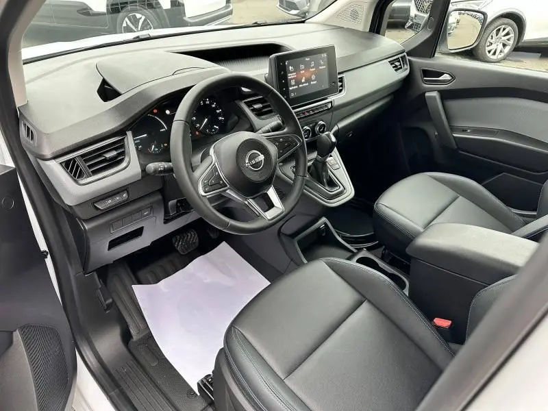 Intérieur du Nissan Townstar L1 EV 2024 vu côté conducteur, avec tableau de bord moderne et sièges noirs en cuir.