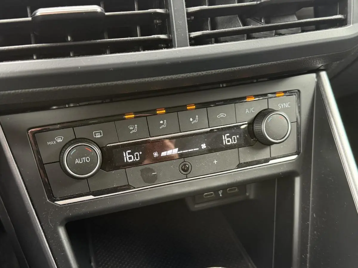 Gros plan sur la console centrale noire de la Volkswagen Polo 1.0 TSI R-Line 2021, affichant la climatisation automatique à 16°C.