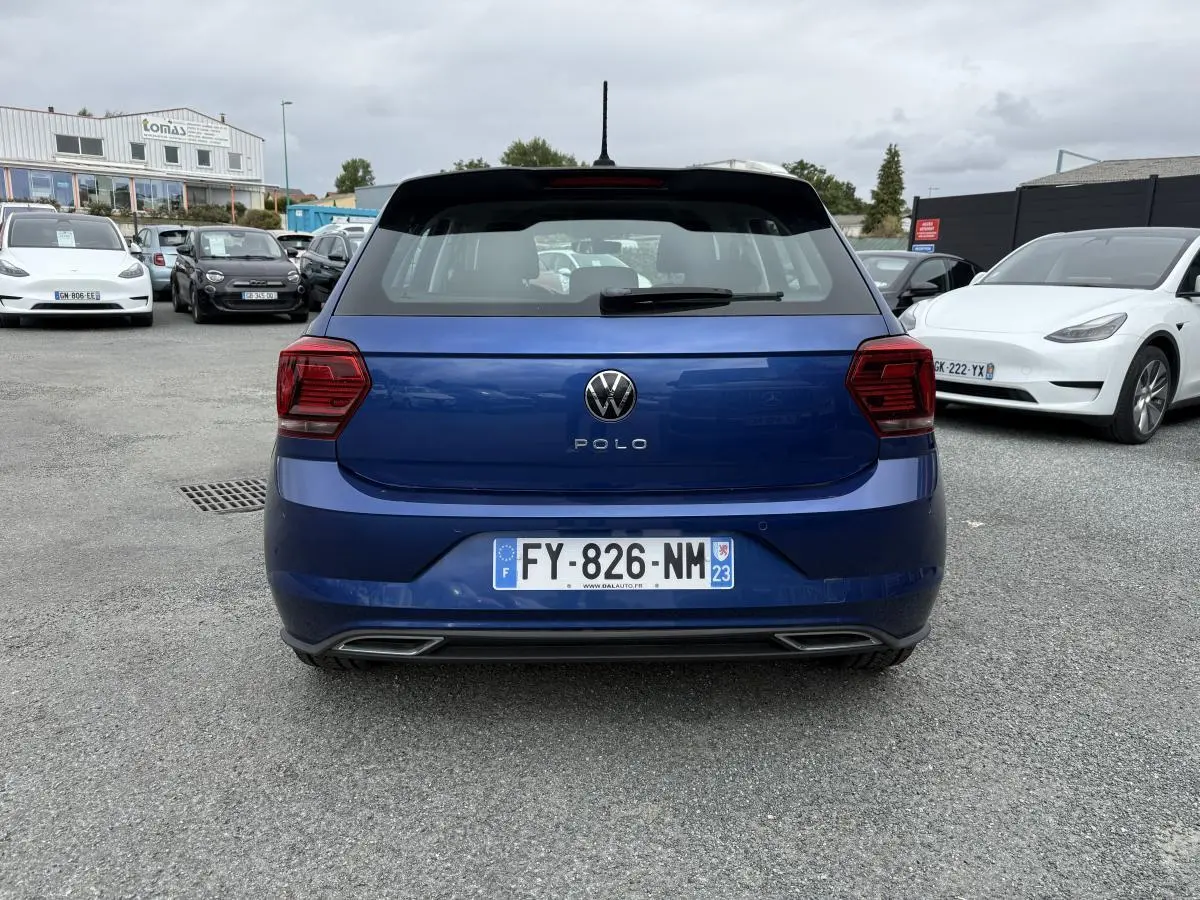 Vue arrière d'une Volkswagen Polo bleu métallisé avec logo et feux arrière foncés, immatriculée en France.
