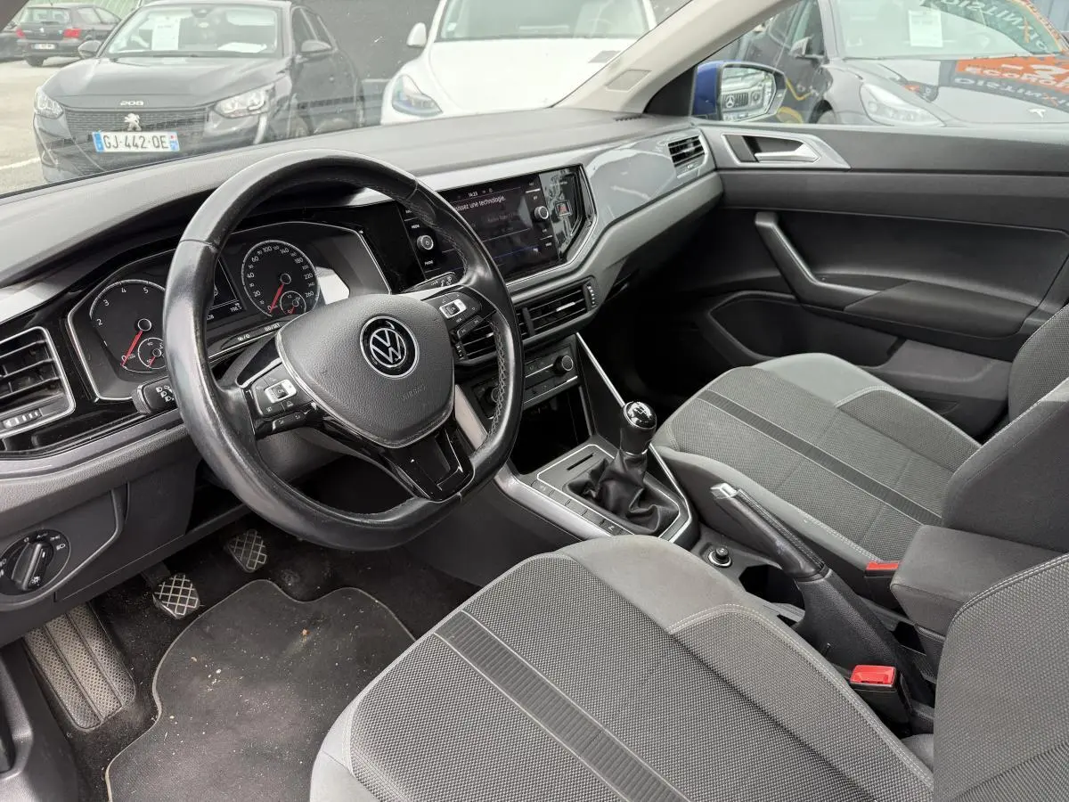 Intérieur avant de Volkswagen Polo 1.0 TSI 2021, siège tissu sport gris et volant trois branches noir.