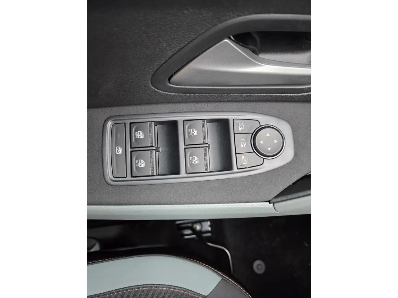 Gros plan sur les commandes des vitres électriques et rétroviseurs sur la porte côté conducteur du Dacia Bigster blanc glacier.