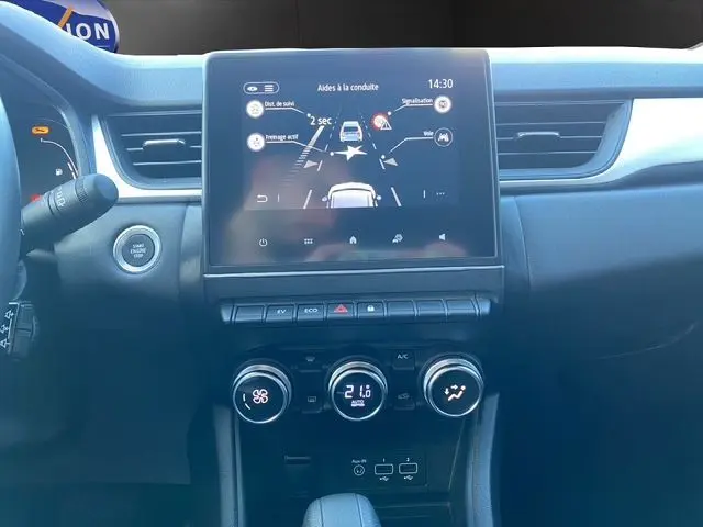 Vue centrée sur l’écran tactile et la console centrale du Renault Captur E-Tech gris Cassiopée, affichant les aides à la conduite.