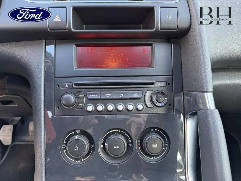 Vue rapprochée du tableau de bord central noir du Peugeot 3008 1.6 HDi112 FAP Style avec commandes radio et climatisation.