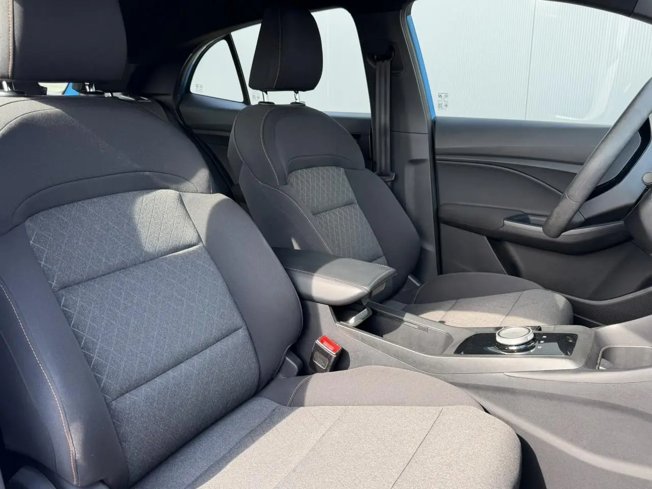 Vue intérieure côté avant droit du MG3 2025, sièges en tissu noir avec accoudoir central et console moderne.