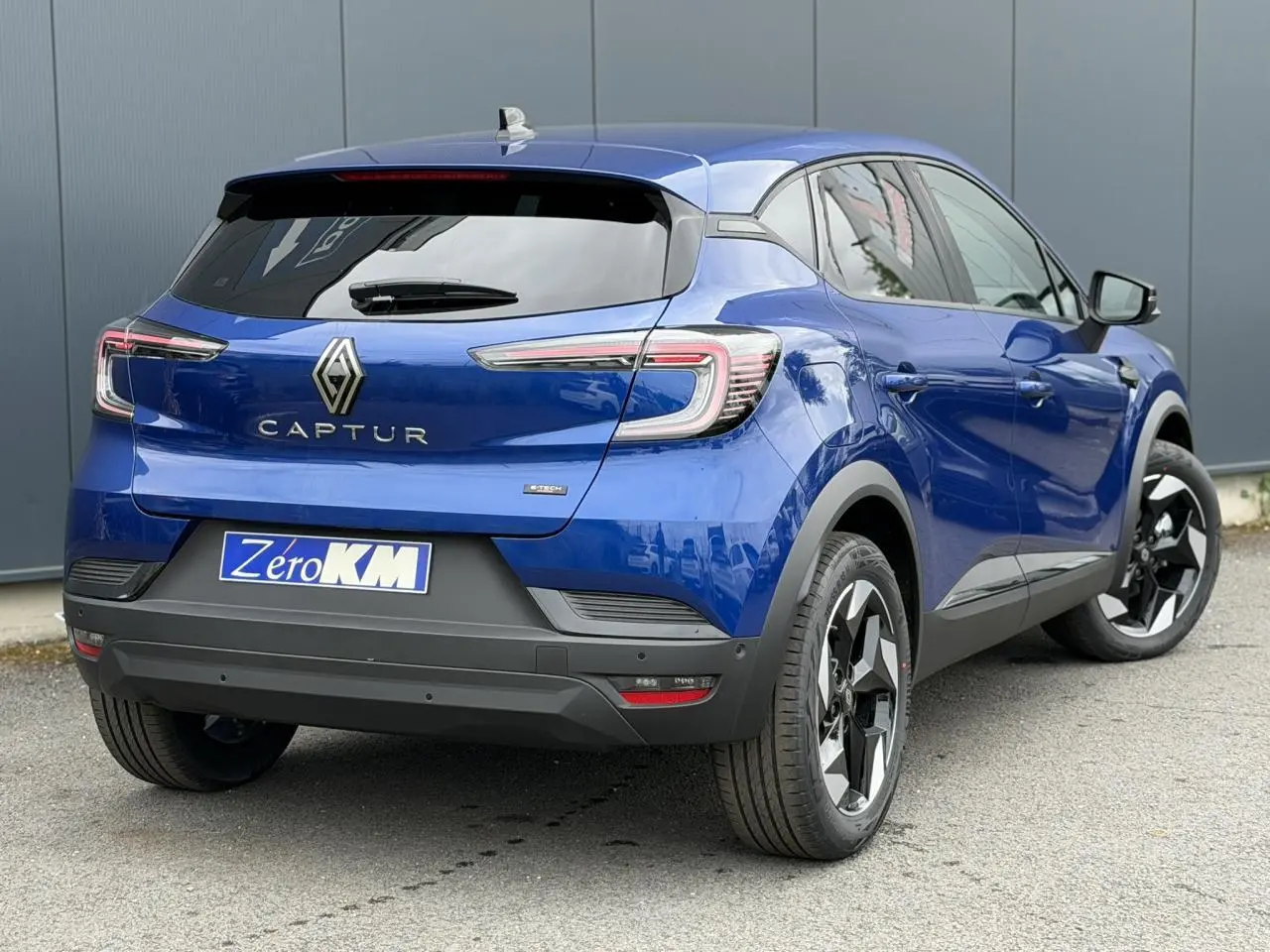 Vue 3/4 arrière droite du Renault Captur 2026 bleu Iron avec jantes aluminium noires et feux LED distinctifs.