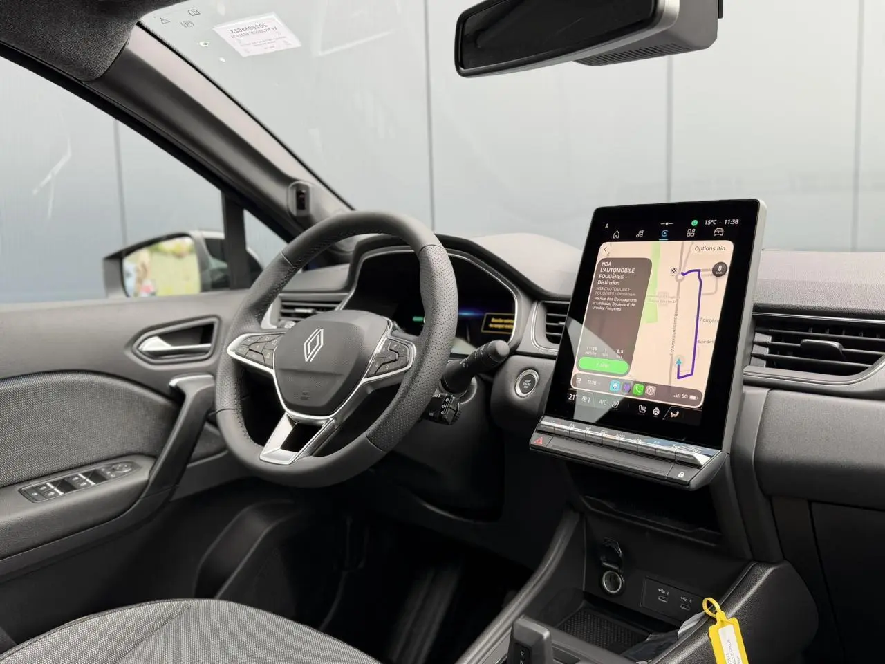 Vue intérieure côté conducteur du Renault Captur 2026, volant multifonction et grand écran tactile central allumé.