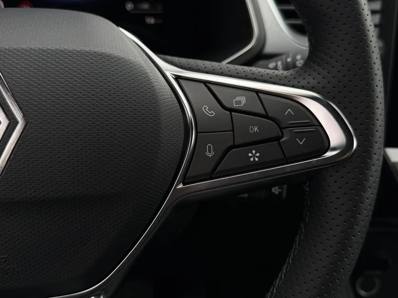 Gros plan sur les commandes à droite du volant perforé noir du Renault Captur hybride 2026.