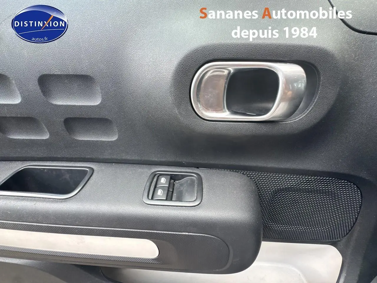 Poignée intérieure et commandes des lève-vitres côté gauche d'une Citroën C3 noire version 1.5 BlueHDi 2023.